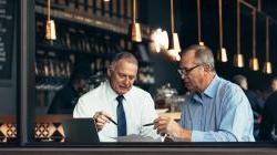 A male mentor talking to a client in a coffee shop